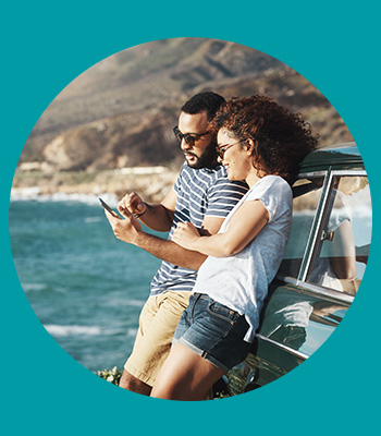 Two people stood in the sun while looking at a phone