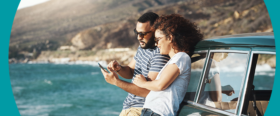 Two people stood in the sun while looking at a phone