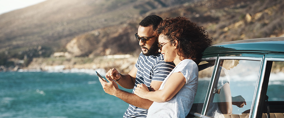 Two people stood in the sun while looking at a phone